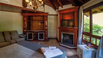 A bedroom with a bed, a TV, a fireplace, and a window with a view.