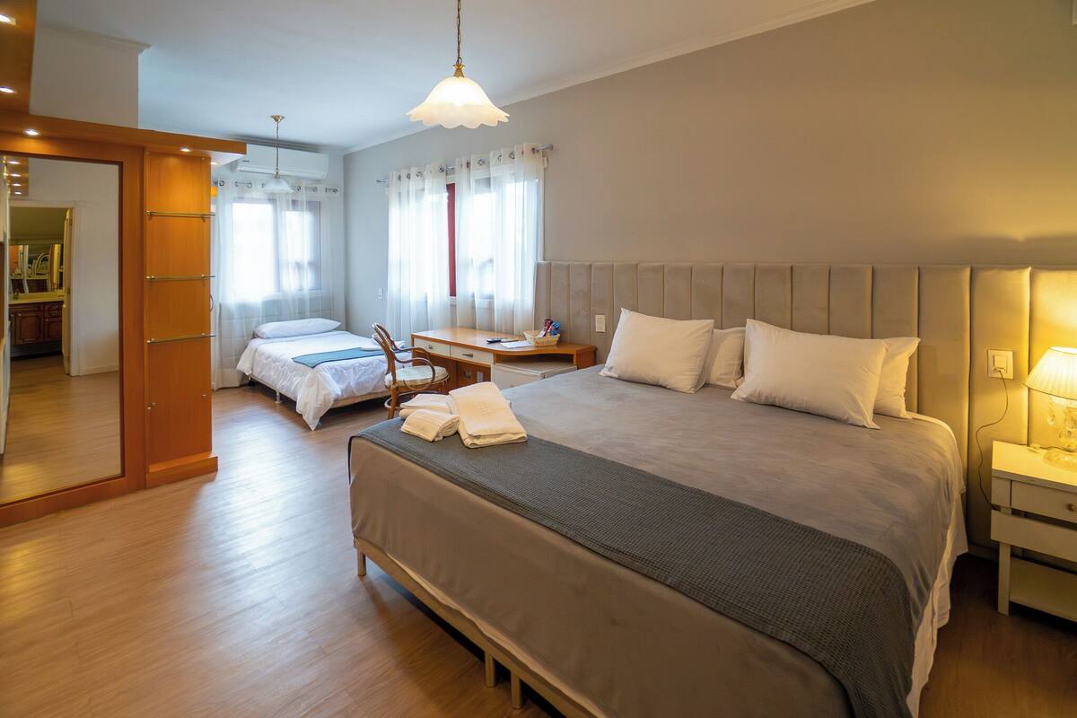 Une chambre d’hôtel avec un grand lit, un lit plus petit, un bureau et une chaise.