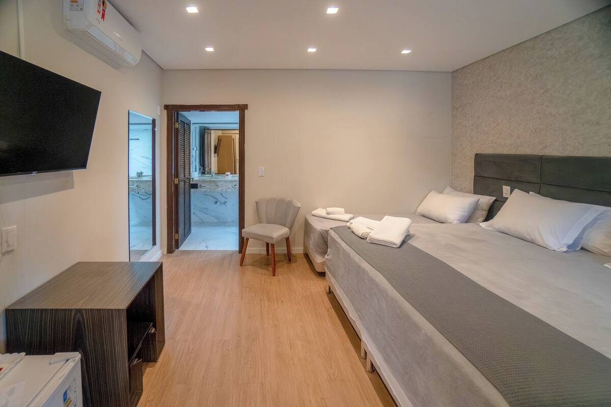 Une chambre d’hôtel avec un lit, une télévision, une chaise et un bureau.