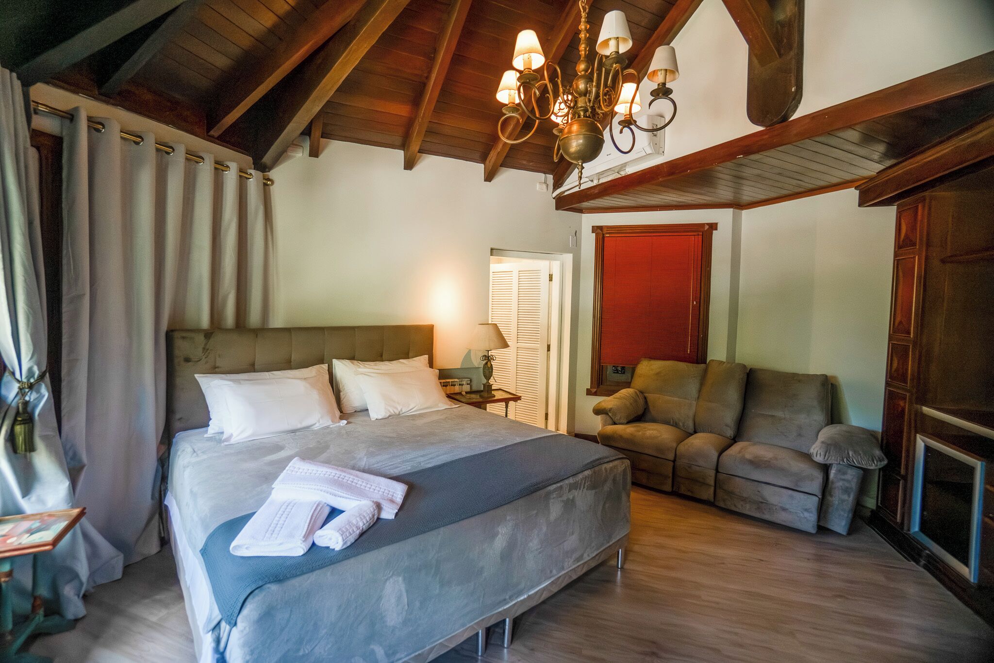 Une chambre à coucher avec un grand lit, un canapé, un lustre et une cheminée.