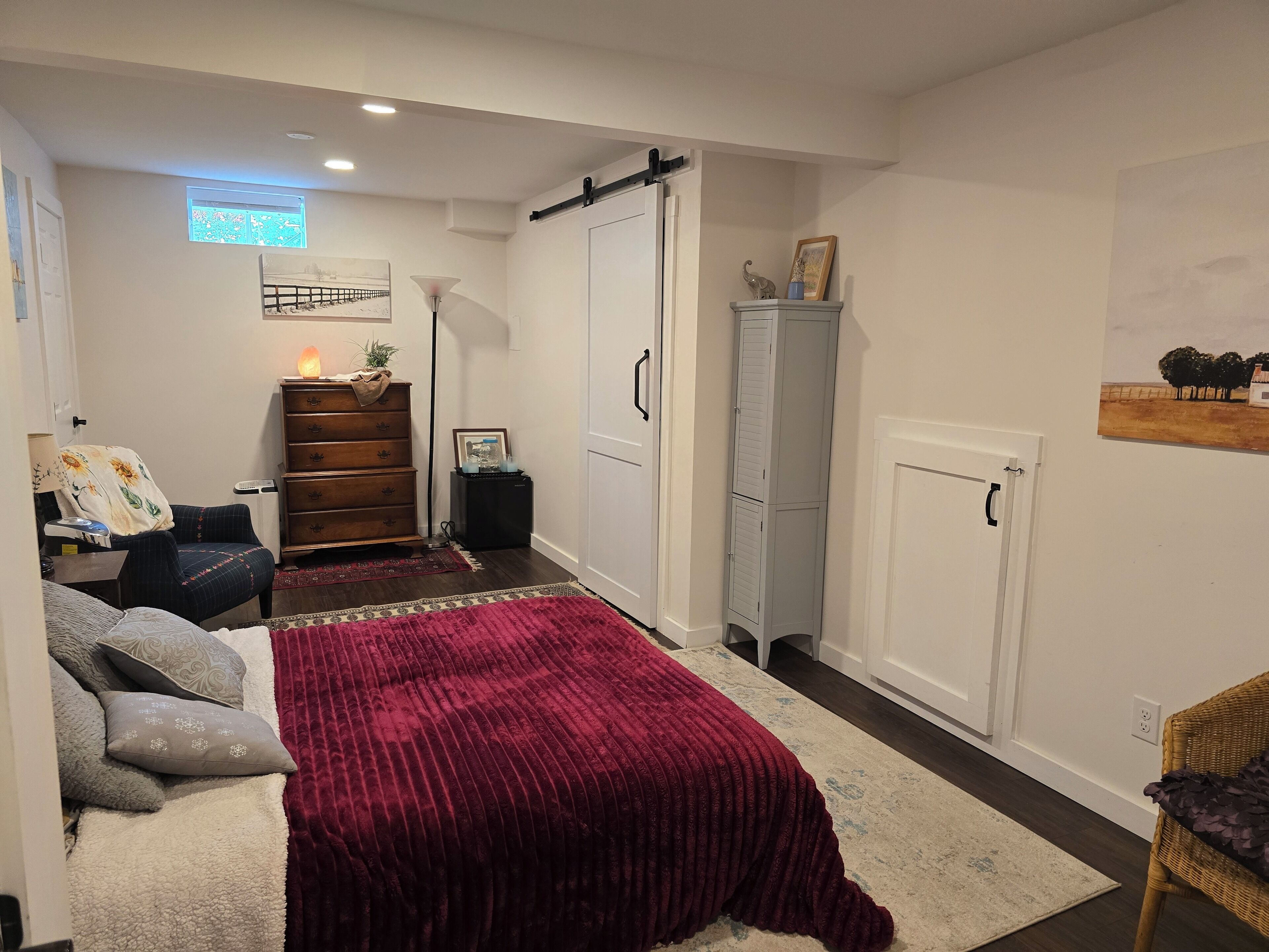 Een compacte slaapkamer met een bed, een dressoir, een kledingkast en een klein bureau.
