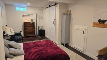 Een compacte slaapkamer met een bed, een dressoir, een kledingkast en een klein bureau.