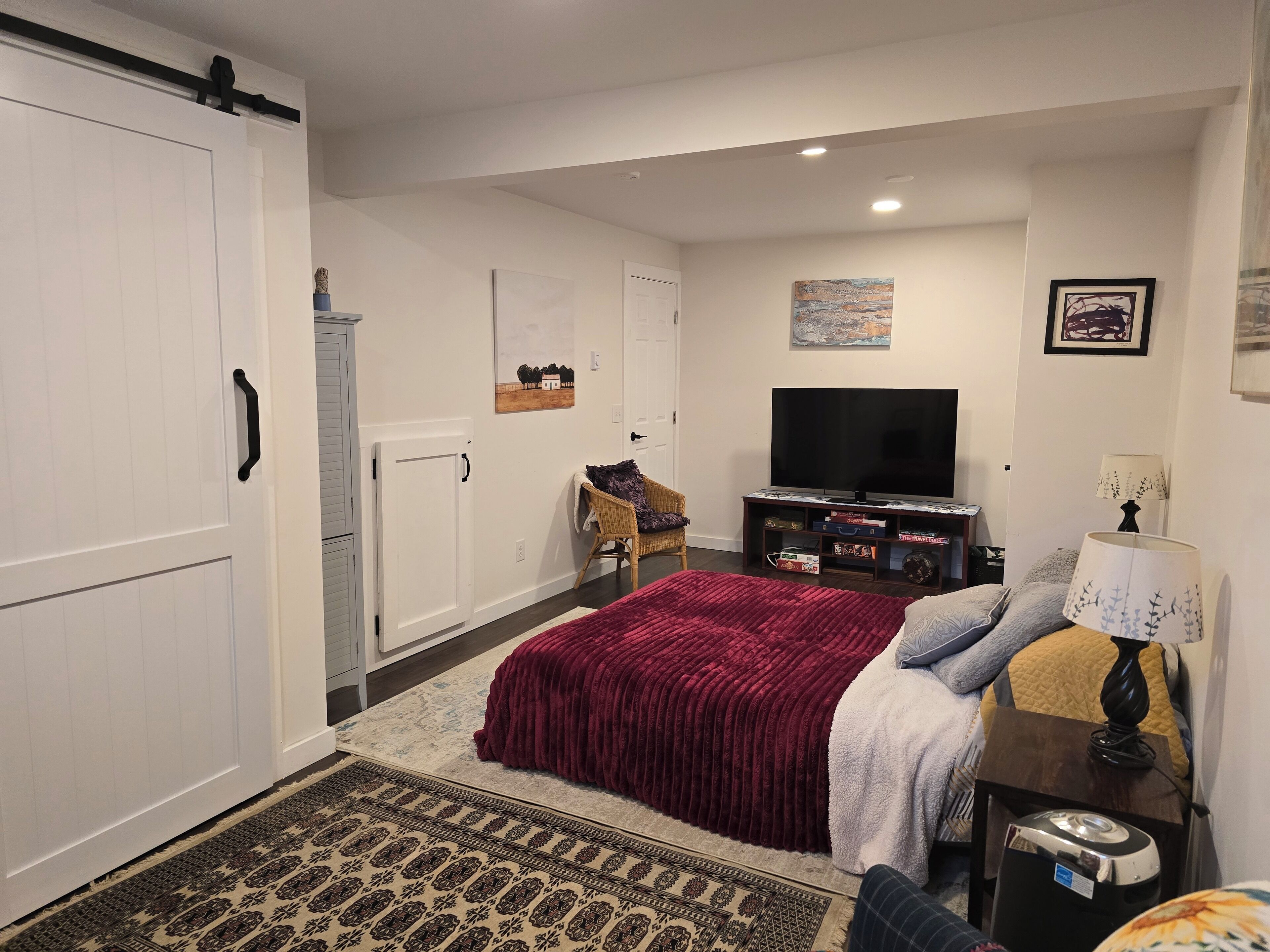 Ein Schlafzimmer mit einem großen Bett, einem Fernseher, einer Kommode und einem Sessel.