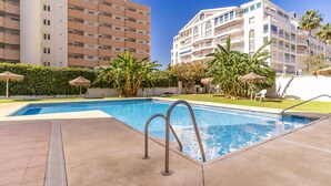 A swimming pool with a clear blue water, surrounded by a paved area and a building with balconies. - Cozy apartment in Fuengirola (Fuengirola)
