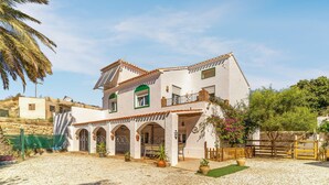 Une maison à deux étages, avec une façade blanche, des encadrements de fenêtres verts et un toit recouvert de tuiles.
