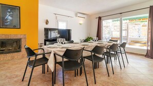Un coin repas avec une table dressée pour six personnes, un téléviseur et une cheminée.