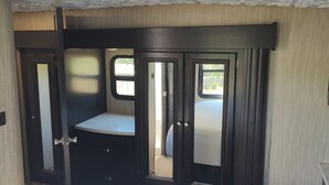 Un intérieur compact aux couleurs sombres, avec un petit coin salon et une porte donnant sur un espace extérieur.