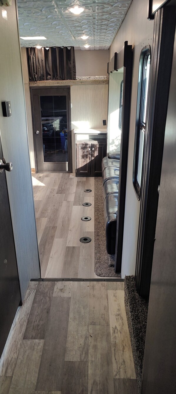 A modern kitchen with a central island, a dining area with a bench, and a view through a glass door to the outside. - 42- foot long Comfortable Camper near Marble Falls! (Marble Falls)