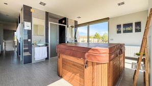 Une salle de bain moderne dotée d’une grande baignoire, d’une douche à parois de verre et offrant une vue sur l’extérieur.