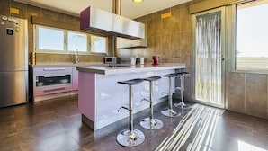 Une cuisine moderne dotée d’un îlot central, de tabourets de bar, d’un réfrigérateur et d’une grande fenêtre.