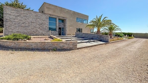 Une maison moderne avec une façade en pierre, de grandes fenêtres et une allée gravillonnée.