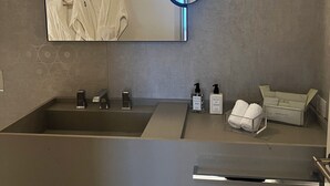 A modern bathroom with a large mirror, a sink, and a towel rack.