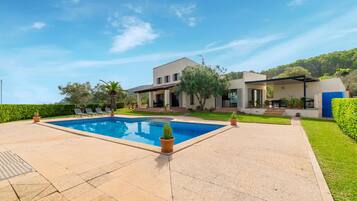 A modern house with a swimming pool, a covered patio, and a well-maintained garden.