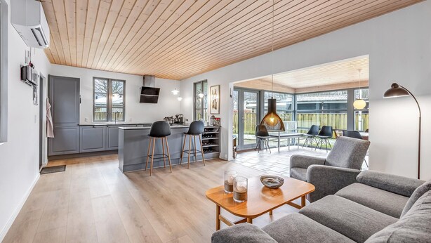 A modern kitchen with a central island, bar stools, and a dining area with a table and chairs.