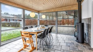 A modern dining area with a large table, chairs, and a wood-burning stove.