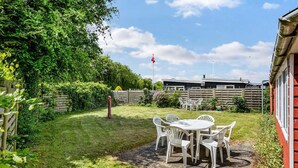 A patio area with a table and chairs, surrounded by a wooden fence and lush greenery. - Lovely home in Haderslev with WiFi (Haderslev)
