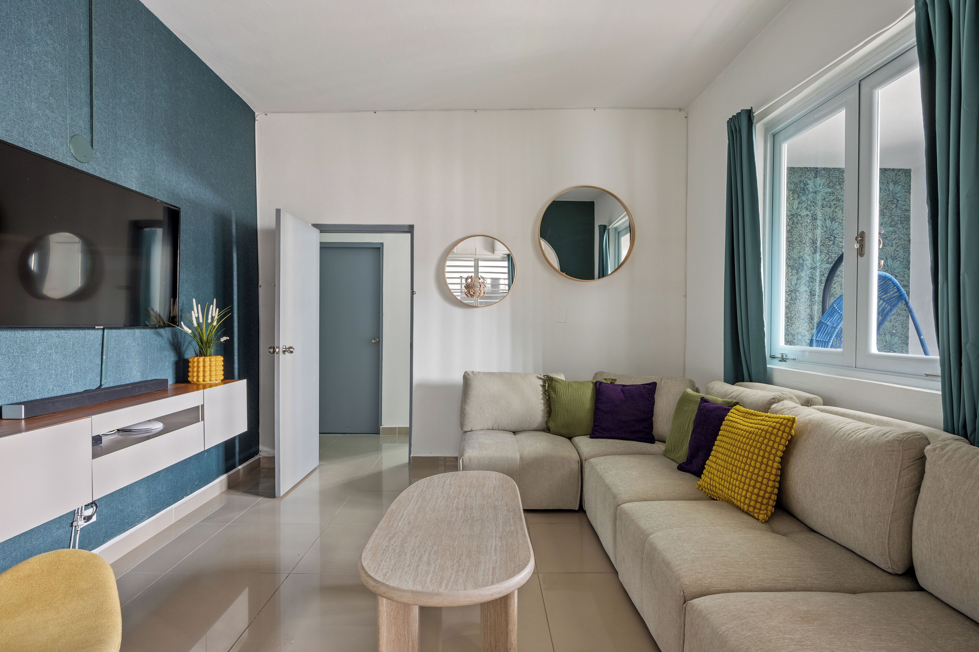 A modern living room with a sofa, a coffee table, and a TV on a wall.