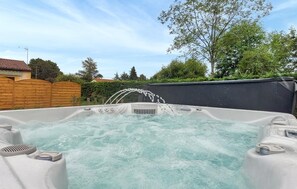 Ein Whirlpool, aus dem Wasser fließt, umgeben von einem Holzzaun und Grünpflanzen.