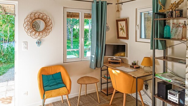 Una habitación acogedora con un escritorio de madera, una silla cómoda, un taburete pequeño y una estantería.