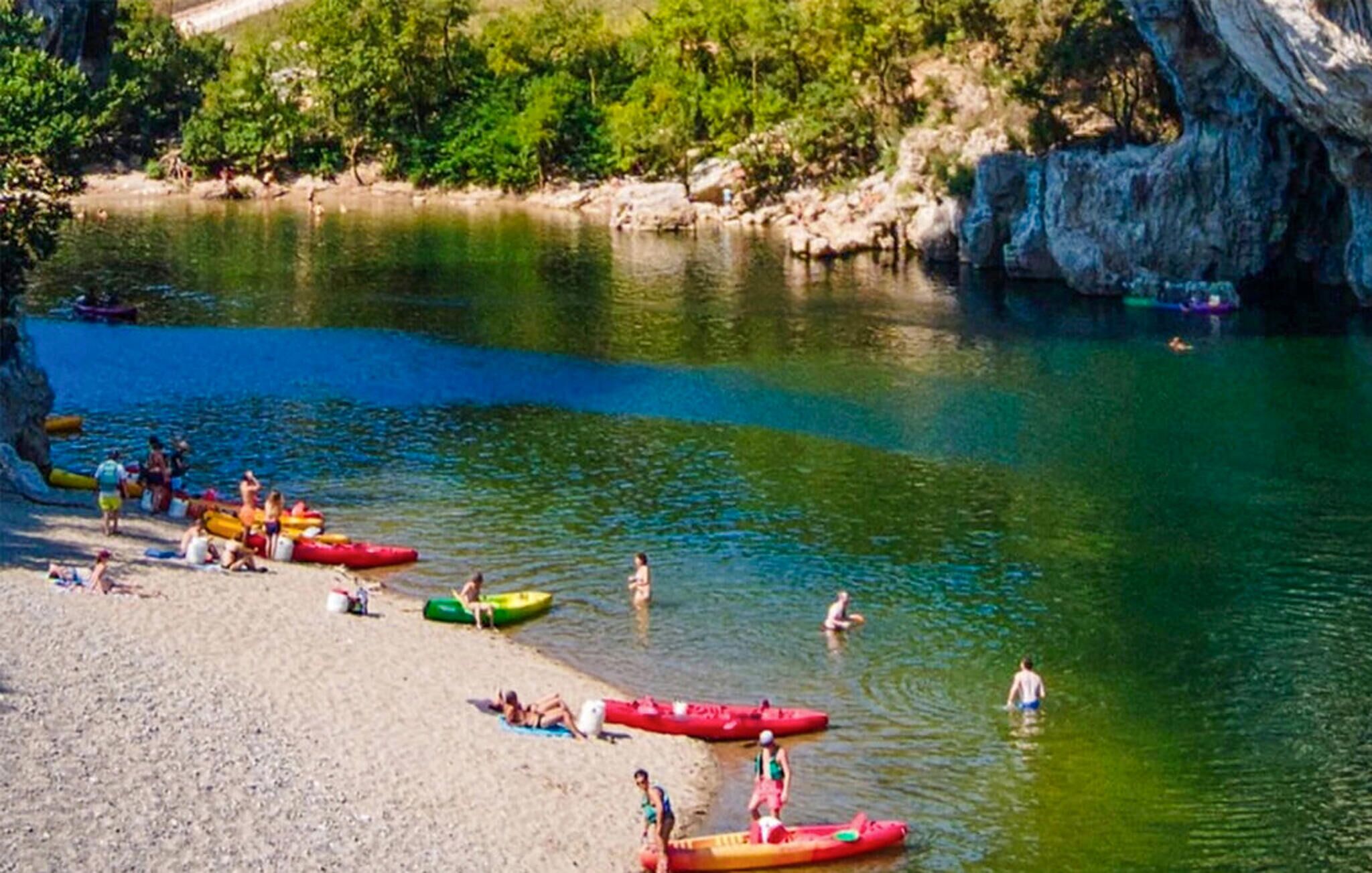 A riverbank with canoes and people engaging in water activities.