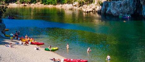 A riverbank with canoes and people engaging in water activities.