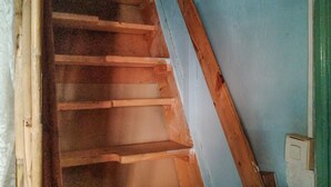 Un escalier en bois avec une rampe, menant à une pièce dont un mur est bleu et la porte est blanche.