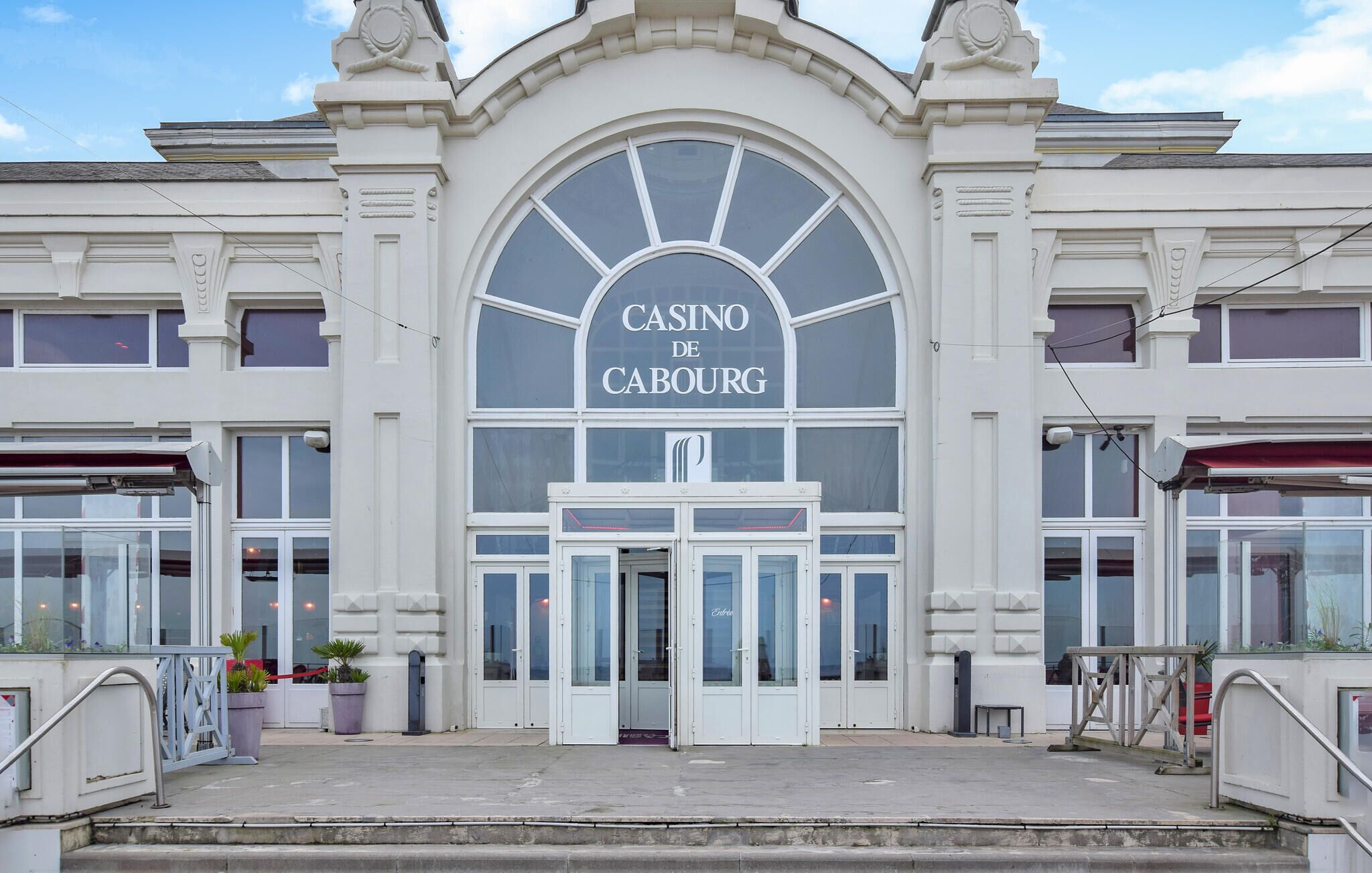 Un bâtiment doté d’une grande entrée en arc de cercle, au-dessus de laquelle on peut lire l’inscription « CASINO DE CABOURG ».