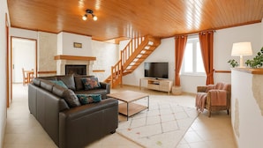 A spacious living room with a leather sofa, a coffee table, a TV, and a staircase leading to an upper level. - 3 bedroom pet friendly home in Joganville (Joganville)