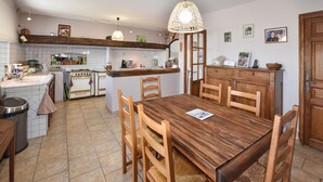A kitchen with a wooden dining table, chairs, and a hanging light fixture.