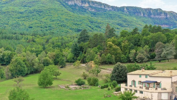 A rural house with a view of a forested mountain.