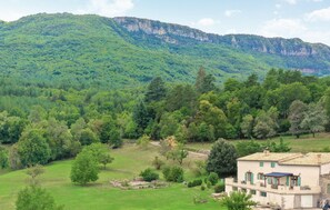 Una casa rural con vistas a una montaña boscosa.