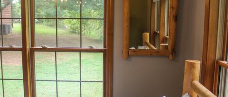 A room with a large window, a wooden headboard, and a mirror on the wall.