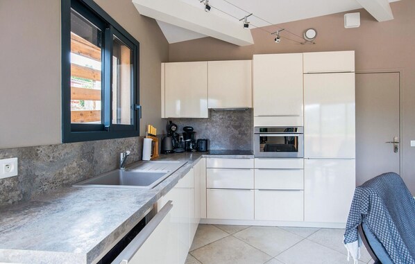 Una cocina compacta con ventana, horno integrado y cafetera.