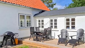 A white house with a red roof, a patio with outdoor furniture, and a barbecue grill. - Beautiful home in ærøskøbing with WiFi (Ærøskøbing)