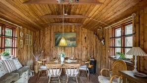 A cozy cabin interior with wooden walls, a dining table with chairs, a sofa, and a fireplace. - Beautiful apartment in Tommerup (Tommerup)