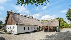 A traditional building with a thatched roof, a gravel courtyard, and potted plants. - Beautiful apartment in Tommerup (Tommerup)