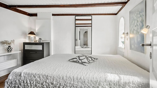 A bedroom with a large bed, a dresser, a mirror, and a wall-mounted light fixture. - Beautiful apartment in Tommerup (Tommerup)