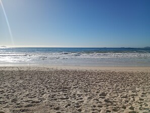 Una playa con huellas en la arena y un cielo despejado.