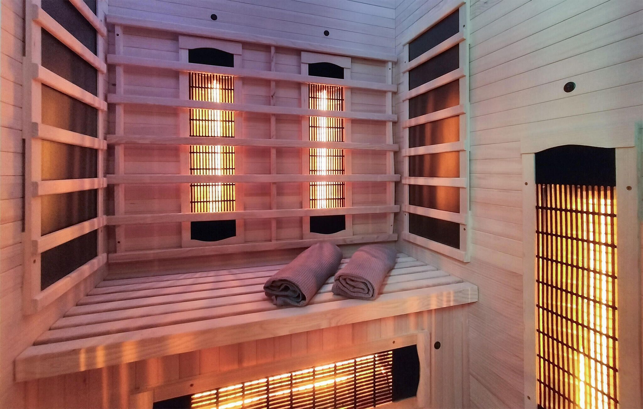 Eine Sauna mit mehreren Bänken, eine Bank mit Handtüchern und einer Holzbodenverkleidung.