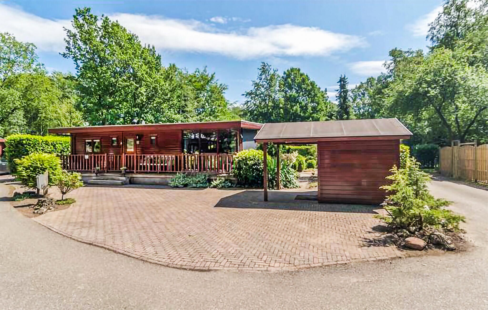 Een eenvoudige houten hut met een terras en een kleine schuur.
