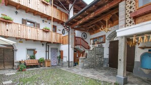 A courtyard with cobblestone flooring, wooden balconies, and stone walls.