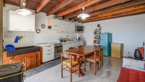 A kitchen with wooden cabinets, a stove, a sink, a dining table with chairs, and a blue refrigerator.
