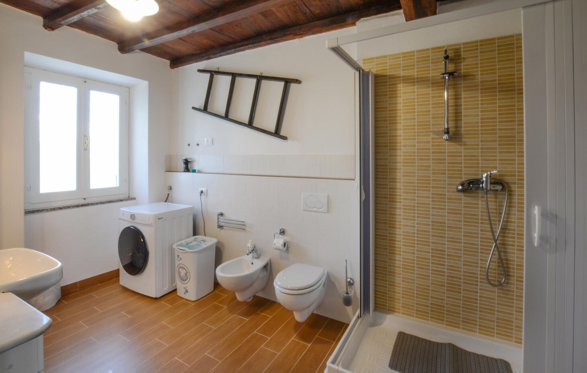 Ein Badezimmer mit Waschmaschine, zwei Toiletten, einem Bidet und einer Dusche.