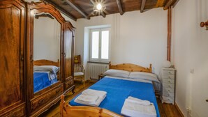 A bedroom with a wooden bed, a wardrobe, a chair, and a window.