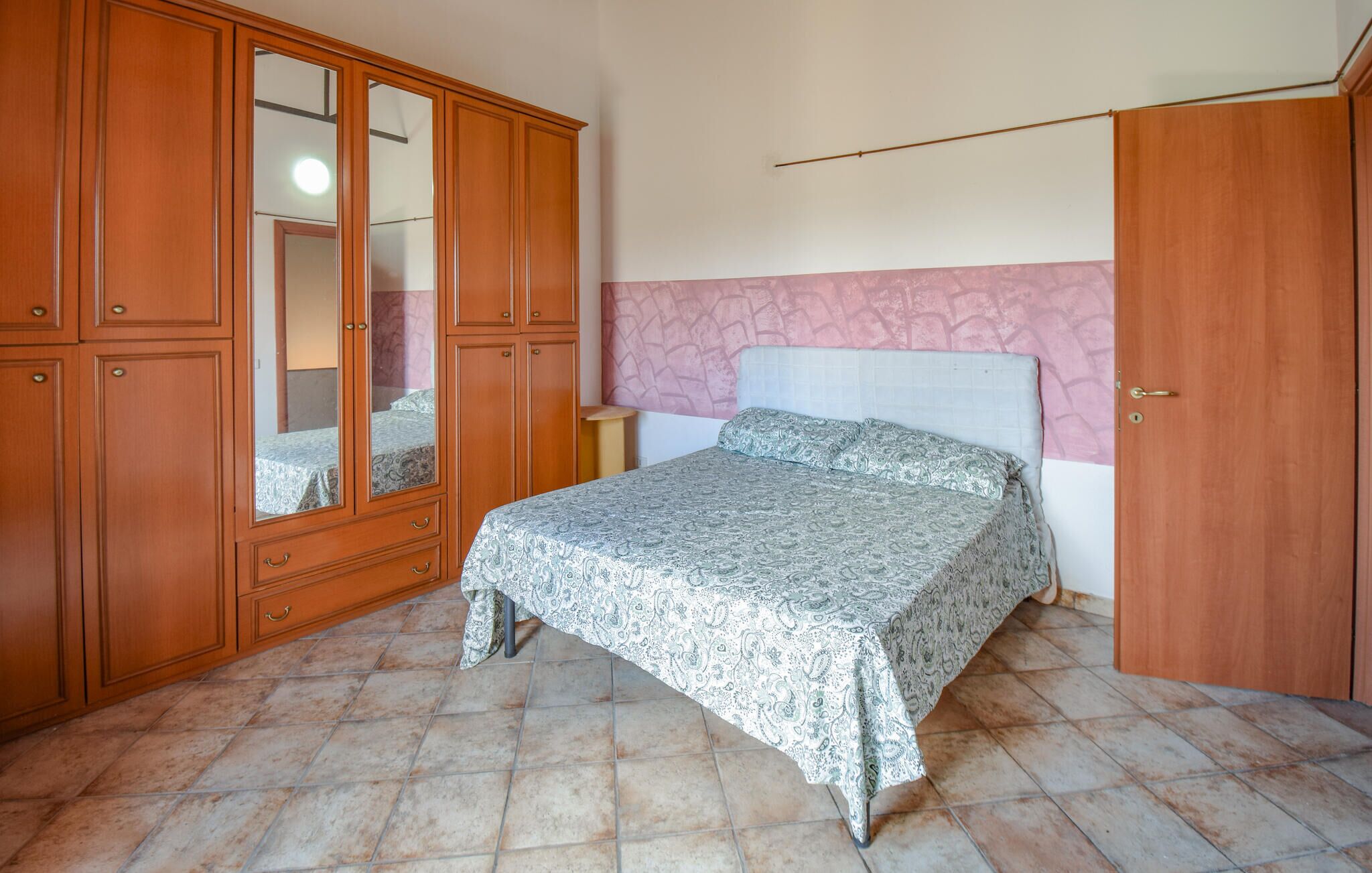 Une chambre à coucher avec un lit, une armoire et un miroir.