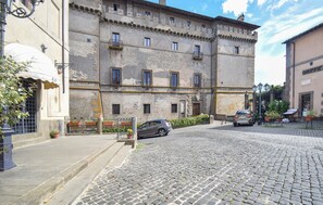 A historic building with a cobblestone street, a café on the left, and a parked car in front. - 3 bedroom amazing home in Vignanello (Vignanello)