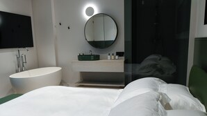 Une chambre moderne avec un grand lit, un miroir rond, un lavabo intégré et un téléviseur à écran plat.