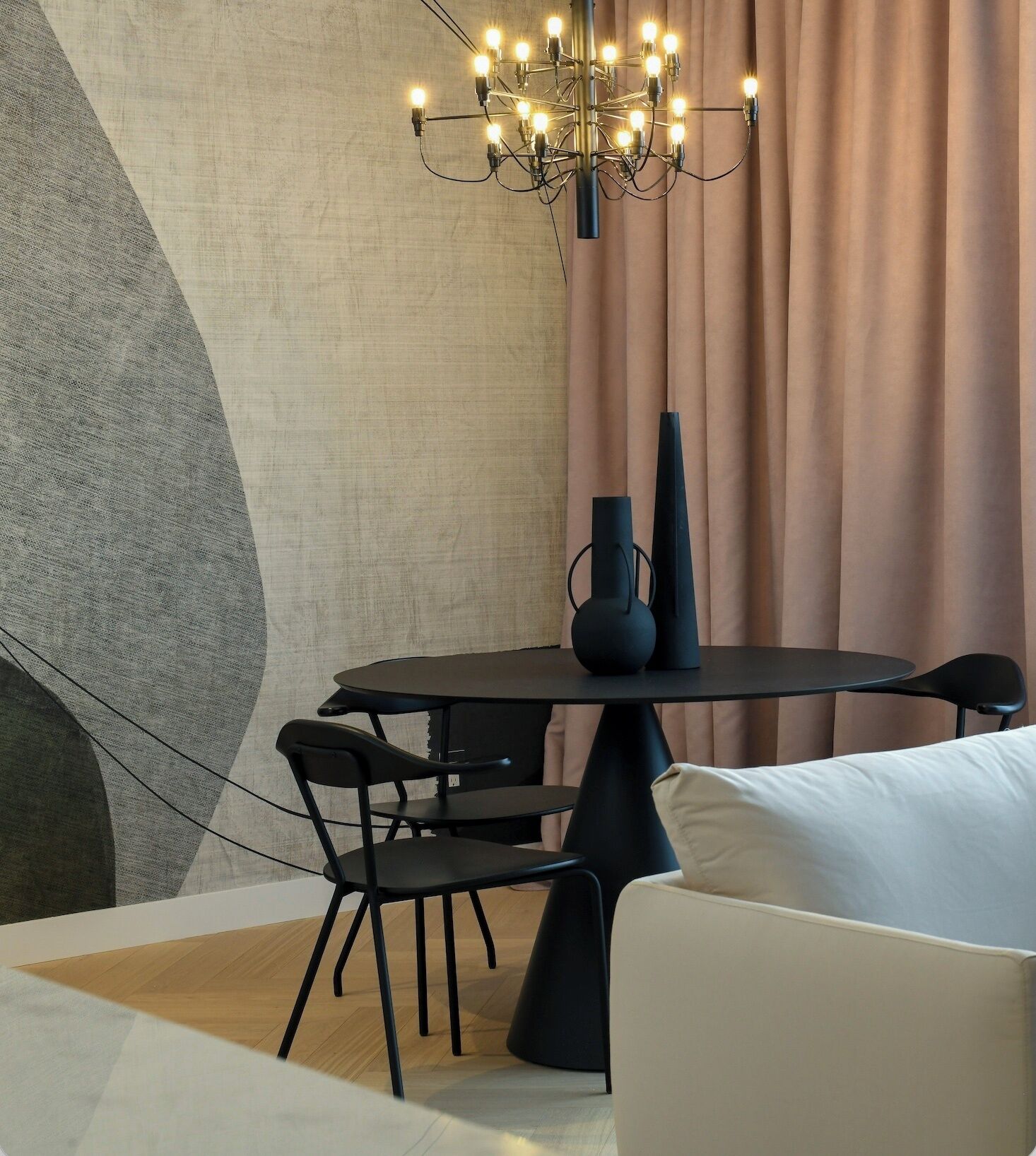 A modern dining area with a round table, black chairs, and a chandelier.