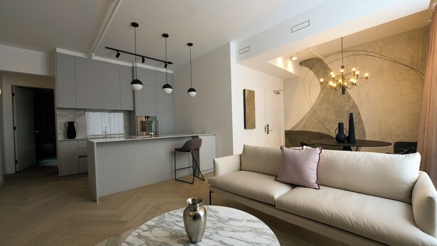 Un espace de vie moderne comprenant une cuisine, un coin repas et un salon avec un canapé et une table basse.