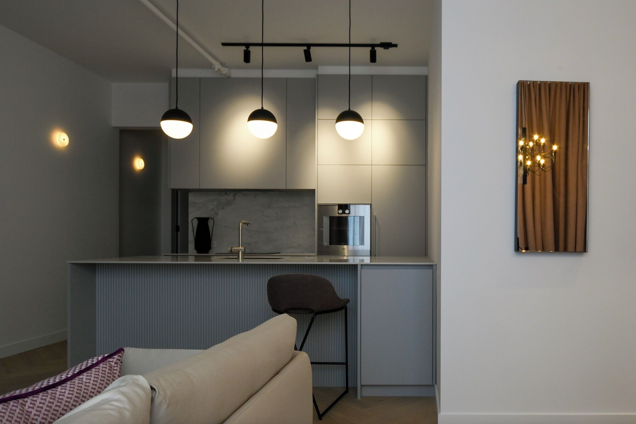A modern kitchen with pendant lighting, a built-in microwave, and a bar stool.
